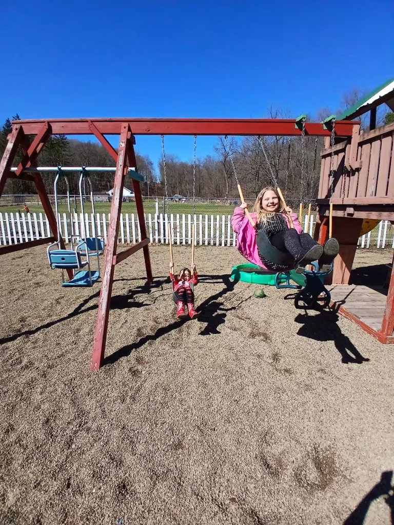 Two girls on a swingset.
